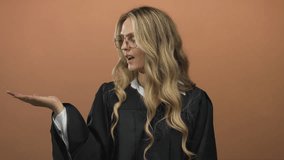 Young blonde woman judge uniform over isolated brown background wall presenting pointed palm in a confident gesture. - Powered by Shutterstock - Get 15% off with code: PIKWIZARD15