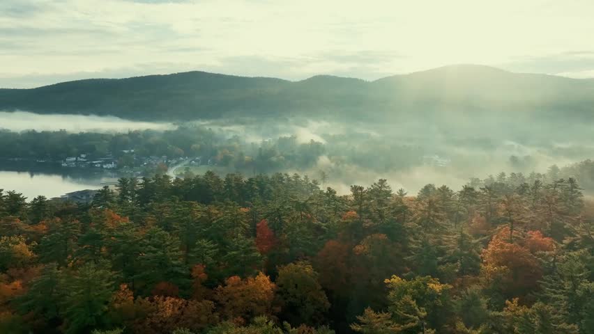 Aerial footage of autumn foliage and morning fog over Lake George, showcasing colorful fall trees and serene natural landscapes.