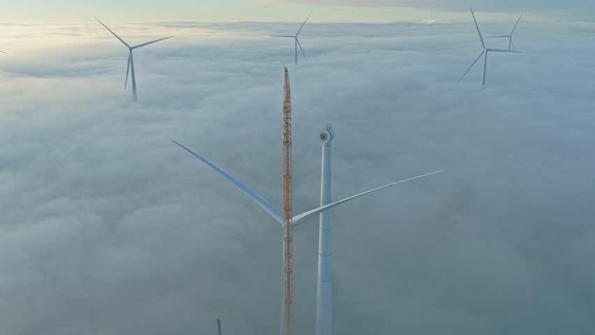 Drone shot of a big crane assembling a wind turbine at an active construction