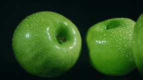 Slow-motion macro zoom-out of four smooth, ripe green apples with water droplets, highlighting freshness and natural textures. - Powered by Shutterstock - Get 15% off with code: PIKWIZARD15