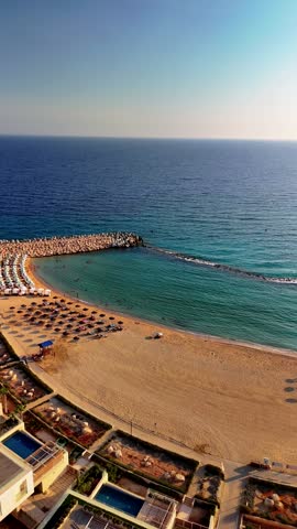 Enjoy a serene view of the beach in Cyprus at sunset, featuring sun loungers on the sand and waves gently lapping at the shore.