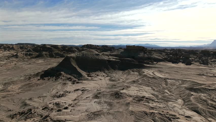 Ischigualasto Provincial Park, also known as Valle de la Luna, displaying a dramatic and dry desert landscape with distinctive barren hills, vast plains, and unusual eroded rock formations drone glide