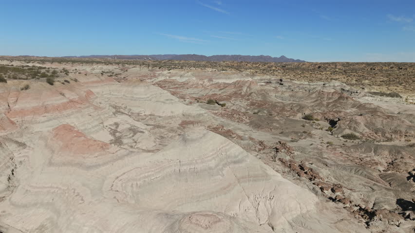 Aerial view of Valle Pintado's dramatic striped rock formations under a clear blue sky in Ischigualasto.