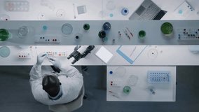 Top view of an African-American scientist using a microscope to examine samples while sitting in a lab, highlighting precision, research, and scientific exploration. - Powered by Shutterstock - Get 15% off with code: PIKWIZARD15