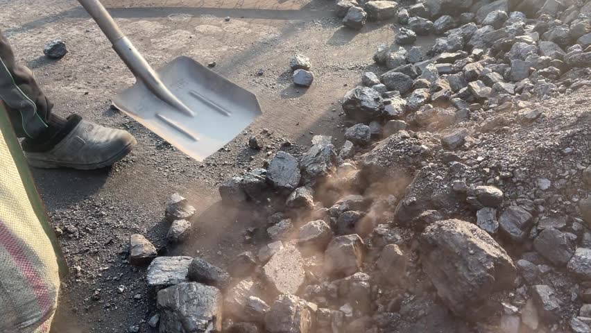 15 October 2025, Fergana, Uzbekistan – Workers manually loading coal outdoors, illustrating labor-intensive industrial or rural work.