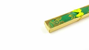 Green fabric scroll with gold floral accents sits inside a decorative box tied with a gold ribbon and a small green bow making it a perfect gift for special occasions or cultural celebrations. - Powered by Shutterstock - Get 15% off with code: PIKWIZARD15