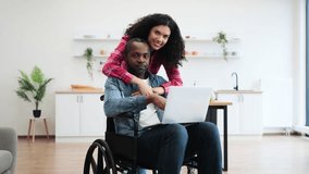 A smiling couple, one using a laptop in a wheelchair, the other embracing him in a modern kitchen setting. - Powered by Shutterstock - Get 15% off with code: PIKWIZARD15