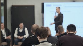 Audience watches blurred presenter in formal attire delivering talk at corporate training event with projector screen - Powered by Shutterstock - Get 15% off with code: PIKWIZARD15