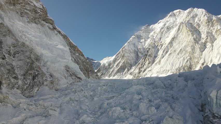 A breathtaking drone angle reveals glacier-carved terrain leading up to Mount Everest, surrounded by towering Himalayan. The crisp, high-altitude atmosphere highlights Nepal’s dramatic scenery.