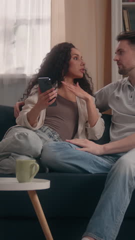 Multiethnic family couple conflict quarrel using mobile phone at home cheating problem Caucasian man male husband Hispanic woman female girl wife browsing smartphone online internet shopping arguing