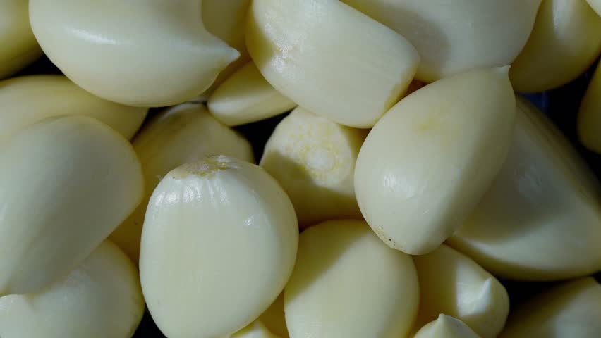 Rotating pile of peeled garlic cloves in top view. Cooking ingredient and essential culinary seasoning