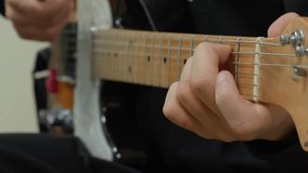 Detailed shot of male hand with fingers pressing strings on maple guitar fretboard with silver frets, black shirt sleeve, shallow depth of field, music practice concept, neutral background. - Powered by Shutterstock - Get 15% off with code: PIKWIZARD15