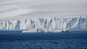 Vast polar shoreline with a drifting iceberg in deep blue water before a towering calving glacier, icy cliffs, and a frozen coast, capturing stark serenity and remote isolation. - Powered by Shutterstock - Get 15% off with code: PIKWIZARD15