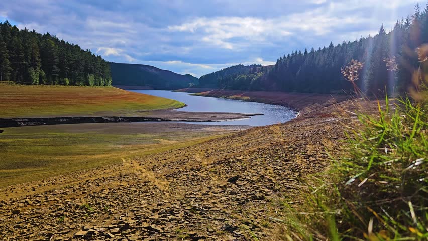 Dried valley with shrinking water pool illustrating severe environmental catastrophe. Parched landscape revealing receding river channel highlighting ecological crisis. Depleted basin showing minimal