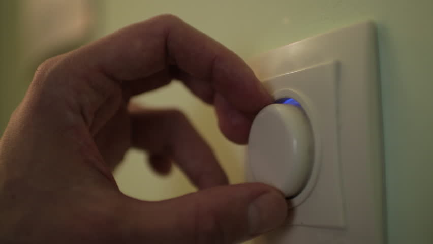 Close-up of a man's hand effortlessly adjusting a wall-mounted dimmer switch to customize the light intensity and conserve energy