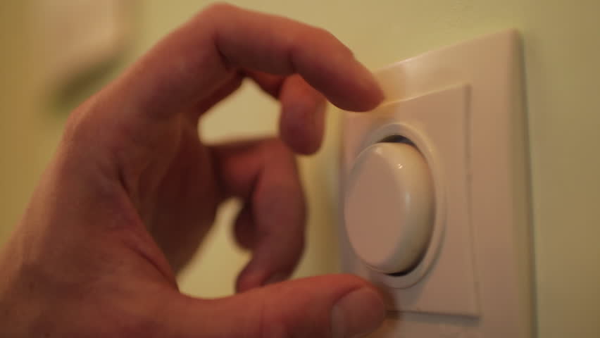 Close-up of a man's hand effortlessly adjusting a wall-mounted dimmer switch to customize the light intensity and conserve energy