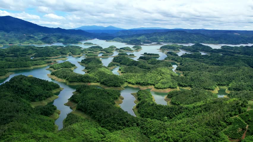 Push-in aerial perspective over Ta Dung Lake, Dak Nong. The stunning maze of densely forested peninsulas and islets mimics the famous Ha Long Bay, showcasing Vietnam