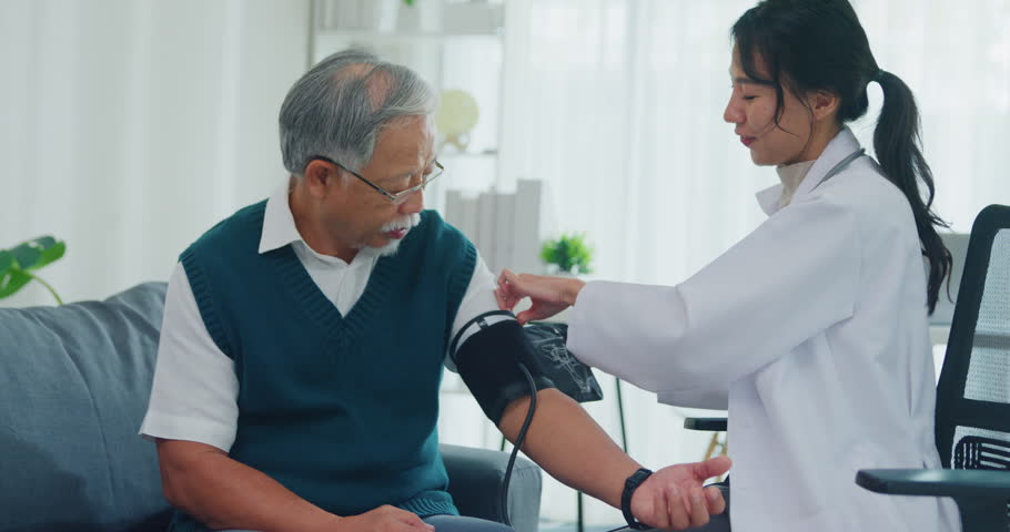 Young Asia female doctor with old man patient using blood pressure consultation or cardiology wellness or hypertension, checkup or healthcare on sofa in health clinic office. Medical worker for care.