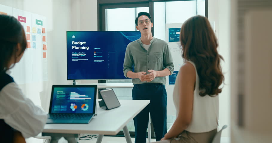 Group of Asian businesspeople work together leads business meeting uses presentation TV with revenue, profit or sale statistics in office. Financial generation z team brainstorm on e-Commerce project.
