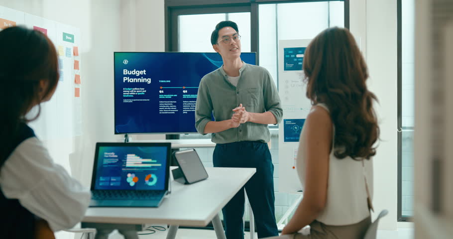 Group of Asian businesspeople work together leads business meeting uses presentation TV with revenue, profit or sale statistics in office. Financial generation z team brainstorm on e-Commerce project.