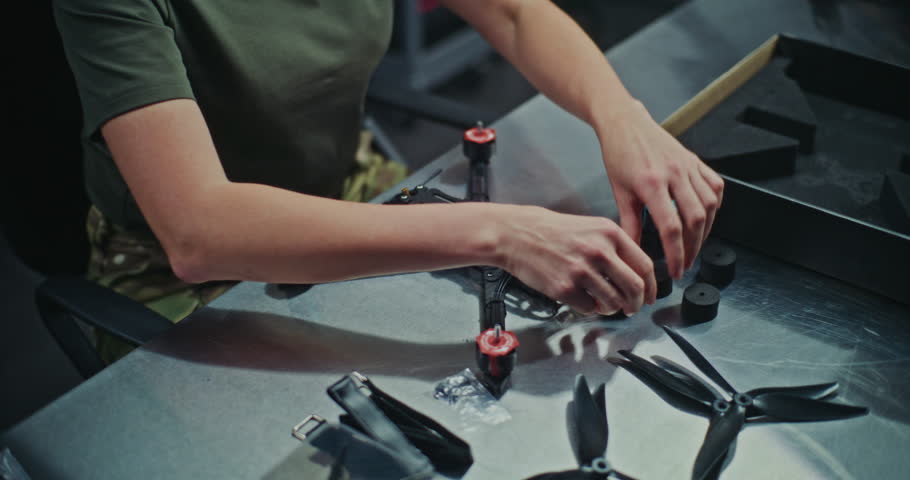Close Up of Female Technician Finalizing Drone. Woman In Military Uniform Finalizing Assembly of FPV Drone, Detailed Finishing Touches and Technical Precision Required For Operational Readiness.