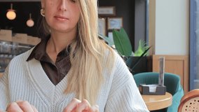 A woman holds a fresh almond croissant while sitting in a cozy cafe. A cup of coffee and warm natural light create a calm, inviting, and comforting atmosphere. - Powered by Shutterstock - Get 15% off with code: PIKWIZARD15