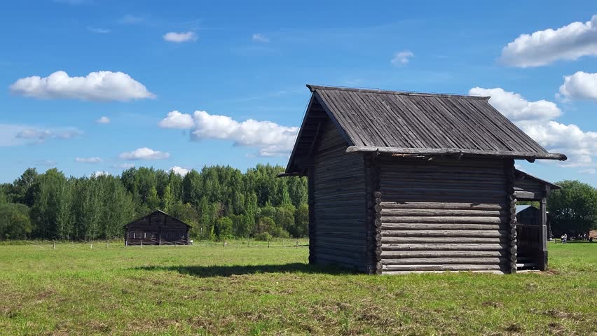 Historic wooden house made of weathered logs, located in a rural area, showing darkened log construction and traditional village architecture.
