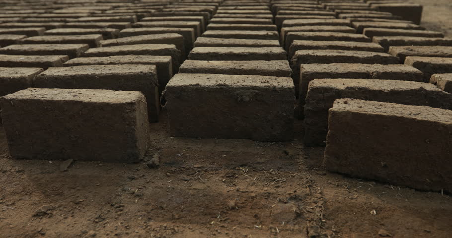Close-up of construction workers laying bricks outdoors, showing manual labor and wall-building activity in sunlight.