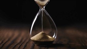 Closeup of sand pouring in hourglass with black background. Sands move through hourglass. the fall of the sand clock dark background. Pass of time and waste time concept. - Powered by Shutterstock - Get 15% off with code: PIKWIZARD15