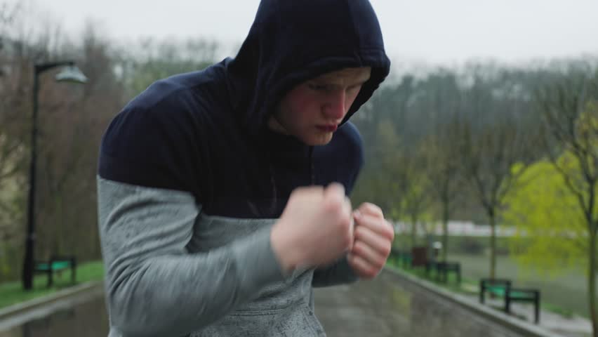Athletic Acrobatics A Sportsman's Intense Boxing Practice in the Rain. The athlete takes his training to the streets, practicing boxing in an open outdoor space. His movements are fluid and graceful,