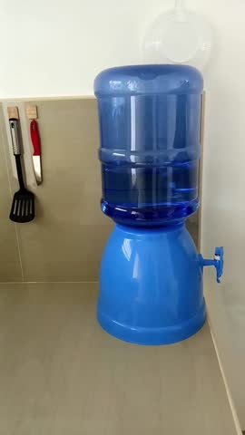 Pouring water from the cooler into a jug. Kitchen. 