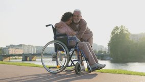 Senior woman in wheelchair walking with caregiver old man on road. Elderly family couple man supporting taking care of paralyzed woman in chair for people with disability outdoor. Rehabilitation - Powered by Shutterstock - Get 15% off with code: PIKWIZARD15