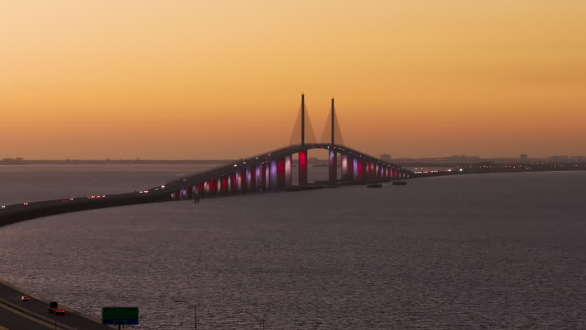 Highway road with driving traffic cars at sunset on Sunshine Skyway Bridge over Tampa Bay in Florida. Transportation infrastructure in USA