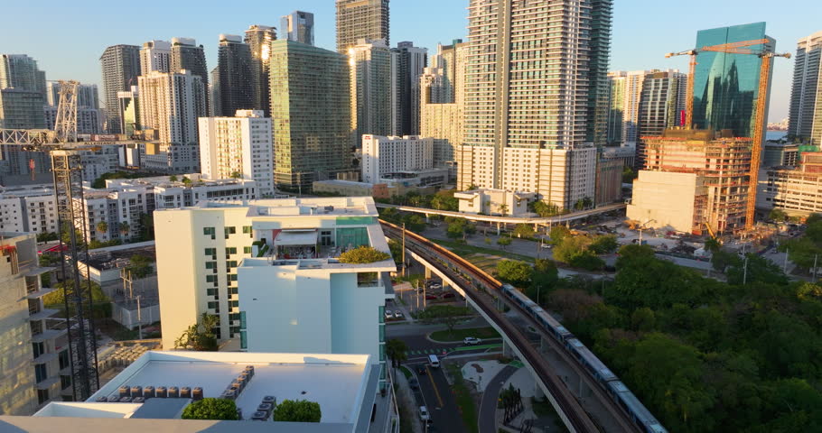 Urban railroad cuts through Miami downtown Brickell district. Public train connecting city between towering American skyscrapers.