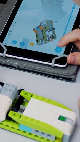 Close-up, the tablet shows an instruction, a model for creating a device from the designer. School children work with a designer at School of Robotics, STEM education.