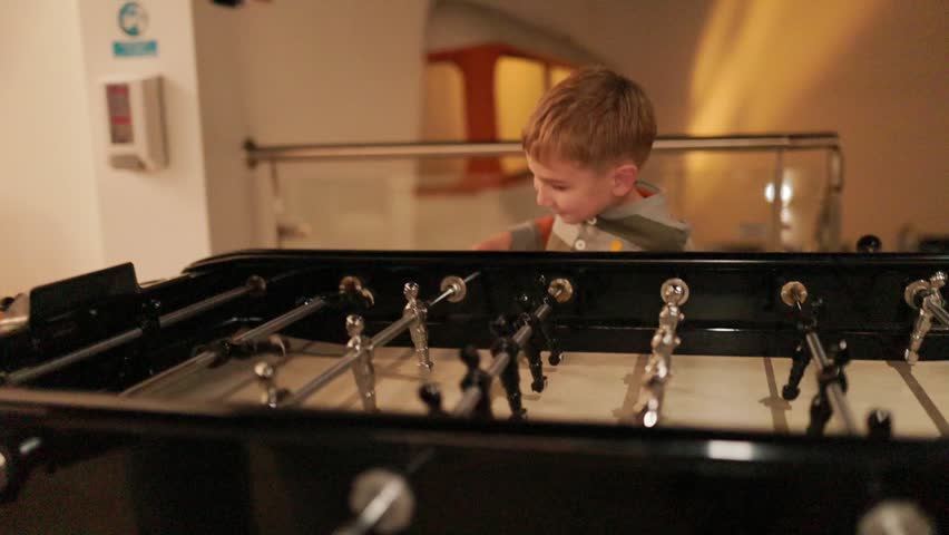 Cheerful little boy playing table soccer