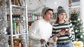  Couple choose food at the Christmas supermarket and use mobile phone. Buying and paying for food with the app and qr code on smartphone - Powered by Shutterstock - Get 15% off with code: PIKWIZARD15