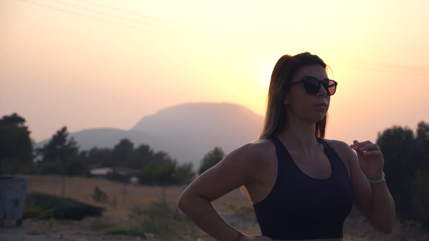 Sporty girl jogging in country road at sunset. Young woman running outdoors. Healthy active lifestyle. Slow motion Close up