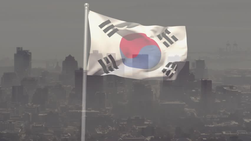 Gusts unfurling South Korean flag on pole, revealing taegeuk and trigrams against hazy skyline. Banner, finial, urban, cityscape, wind, motion, dramatic
