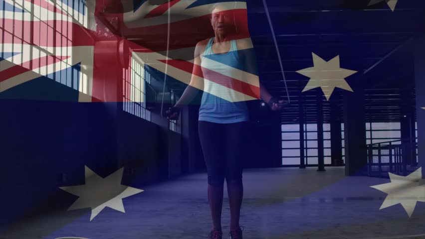 Woman rotating wrists, starting rope swing and skipping for fitness while AUS flag overlaying frame. Jumping, athletic, cardio, industrial, warehouse, naturallight, sidelight