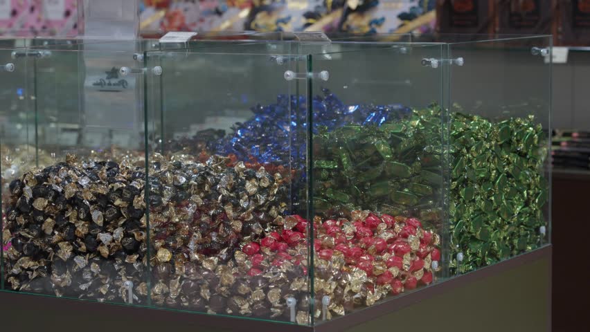 Lots of candies in colorful packages on the shop window. Vibrant wrapped candies gleaming on display plates, showcasing colorful confectionery delicacies within elegant pastry shop interior