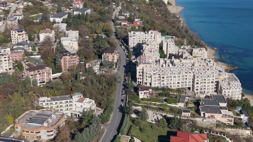 Aerial view of a town surrounded by hills and autumn trees, showcasing residential buildings, roads, and a wide natural landscape.