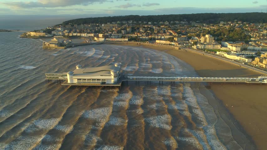 Wide aerial of the Grand Pier at Weston Super Mare surrounded by ripples of waves in the sea in the United Kingdom on s aunny day. High quality 4k footage