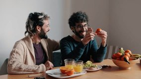 A happy gay couple enjoys a healthy breakfast together at their dining table, sharing a moment of love and affection. - Powered by Shutterstock - Get 15% off with code: PIKWIZARD15