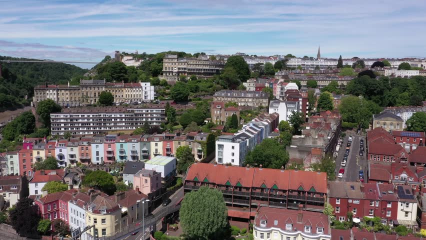 Sideways tracking aerial past houses to reveal the Clifton Suspension Bridge and Avon River in Bristol, England. High quality 4k footage