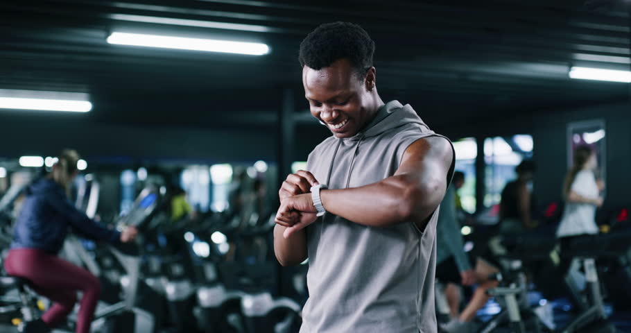 Smart watch, training or man in gym, fist pump or workout with digital app to track progress. Athlete, celebration or person in health center, target or achievement with fitness and exercise goals