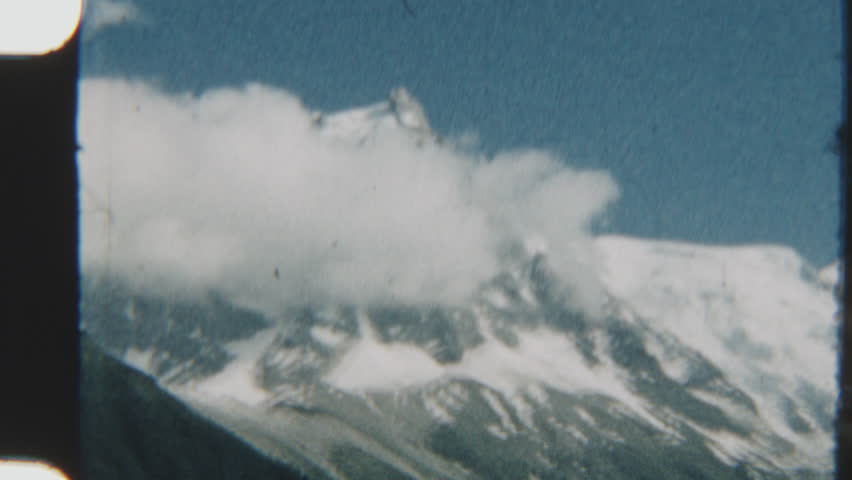Grainy 8mm footage captures the majestic Mont Blanc in daylight, with snow-capped peaks under the sun and vintage film textures evoking a nostalgic, timeless feel