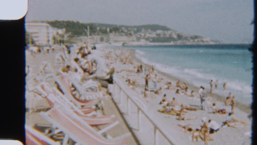 8mm footage of tourists relaxing and sunbathing on a busy beach in Nice, France, with a classic summer coastal vibe