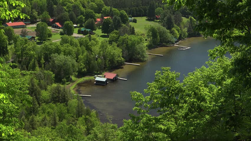 Lakeside retreat with wooden cabins, docks, and lush forest by tranquil waters. Scenic summer vacation spot in Lake of Bays, Ontario.
