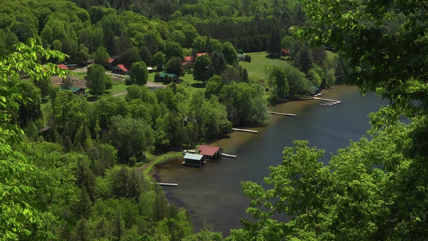 Lakeside retreat with wooden cabins, docks, and lush forest by tranquil waters. Scenic summer vacation spot in Lake of Bays, Ontario.